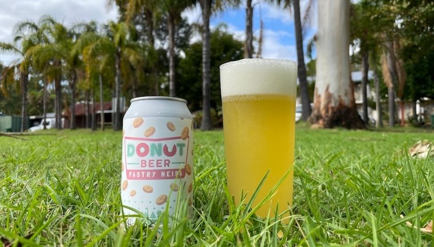 donut beer in a can and a glass on the grass