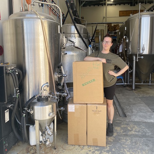 a female brewer with boxes of beer clips